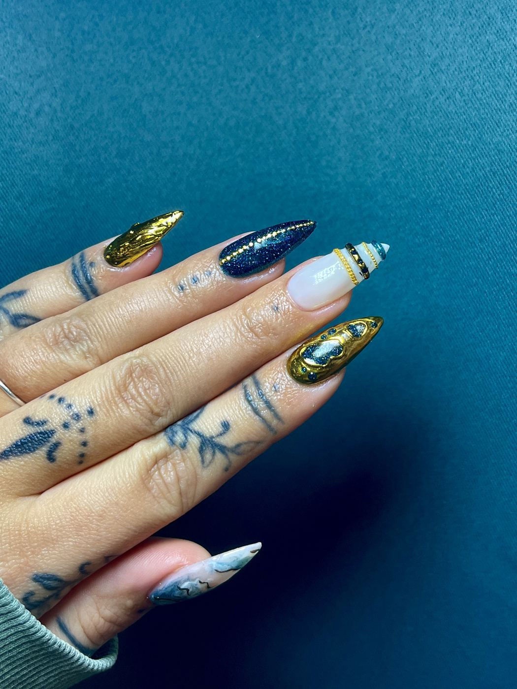 Nail art bleu nuit pailleté et doré chromé, orné de strass