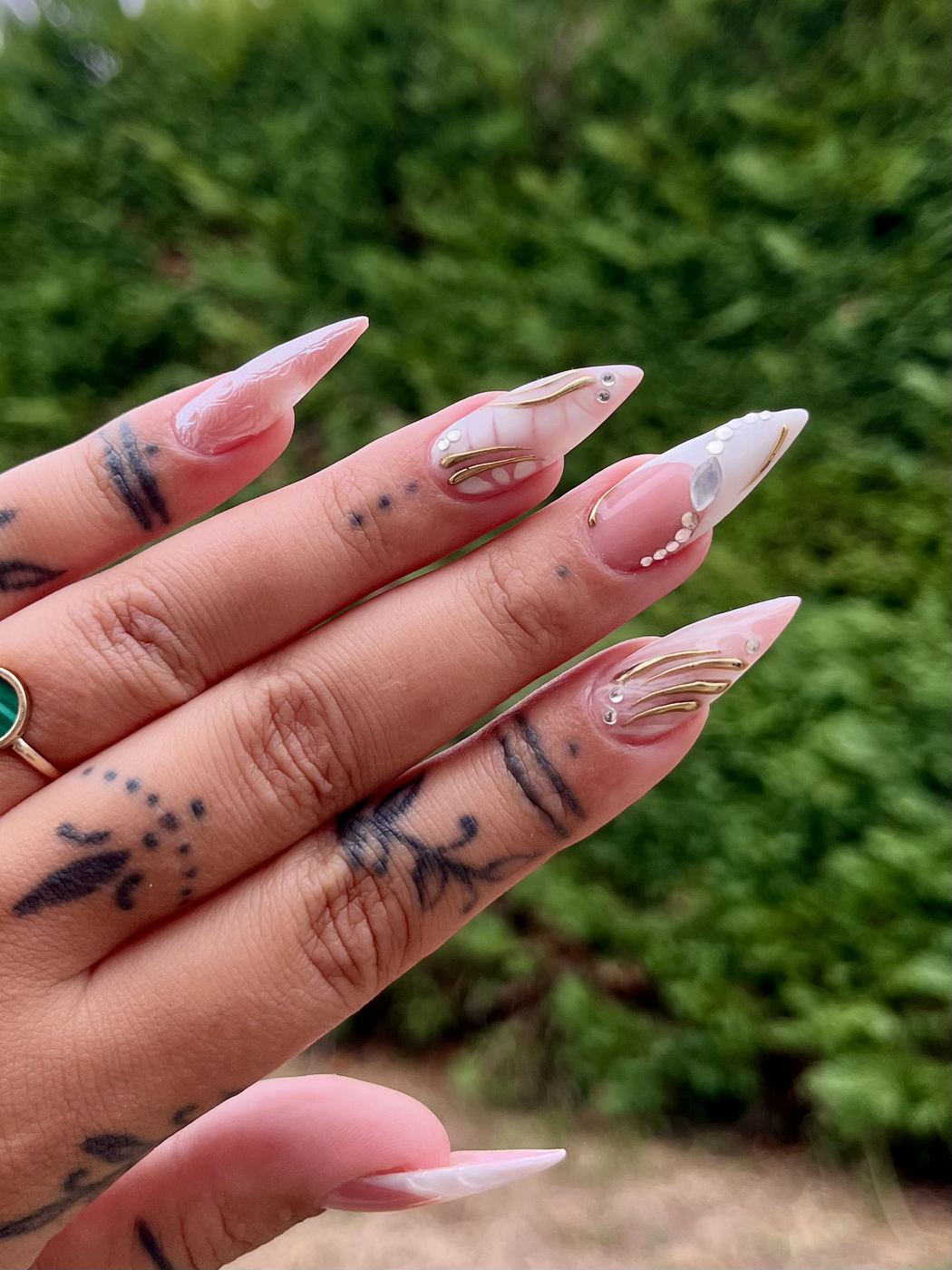 Nail art nude laiteux souligné de lignes dorées et de strass